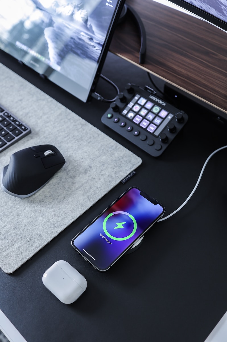 black and gray computer mouse beside black computer keyboard with a phone charging